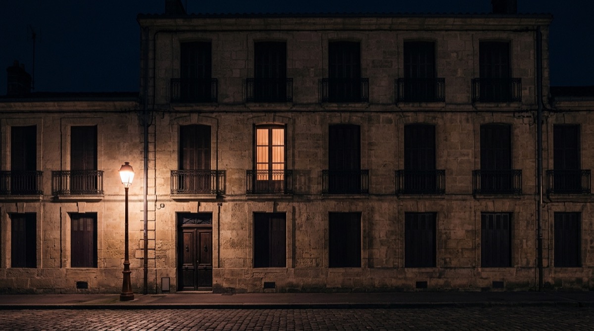 Façade d'un immeuble résidentiel de Dijon de nuit, une seule fenêtre éclairée